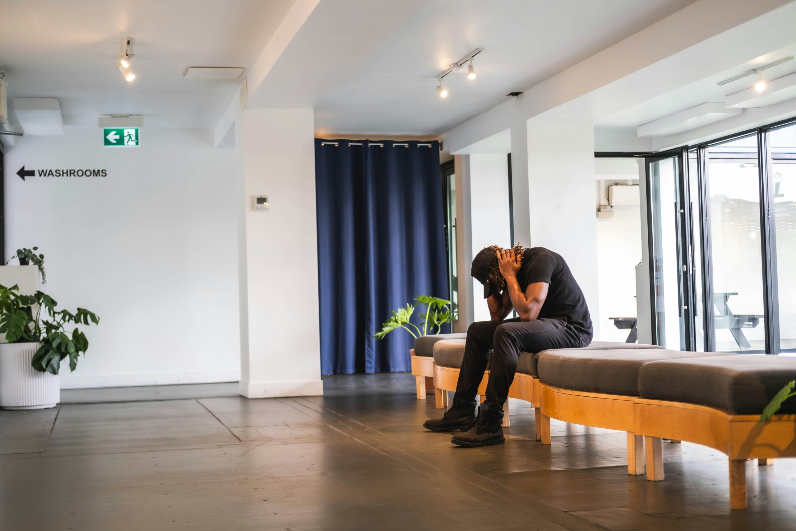 Slouched man holding his head on a couch.