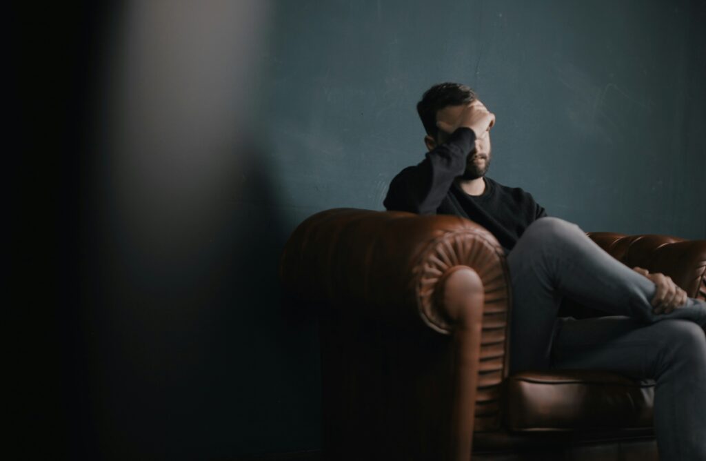 Man looking hopeless on couch.
